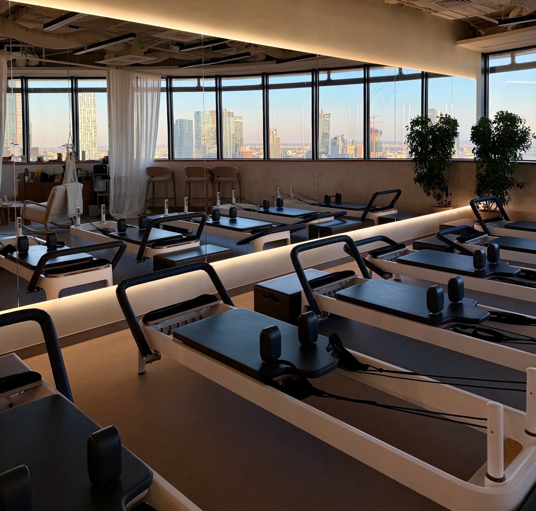 Sala reformer BeShaped z panoramą Warszawy o zachodzie słońca